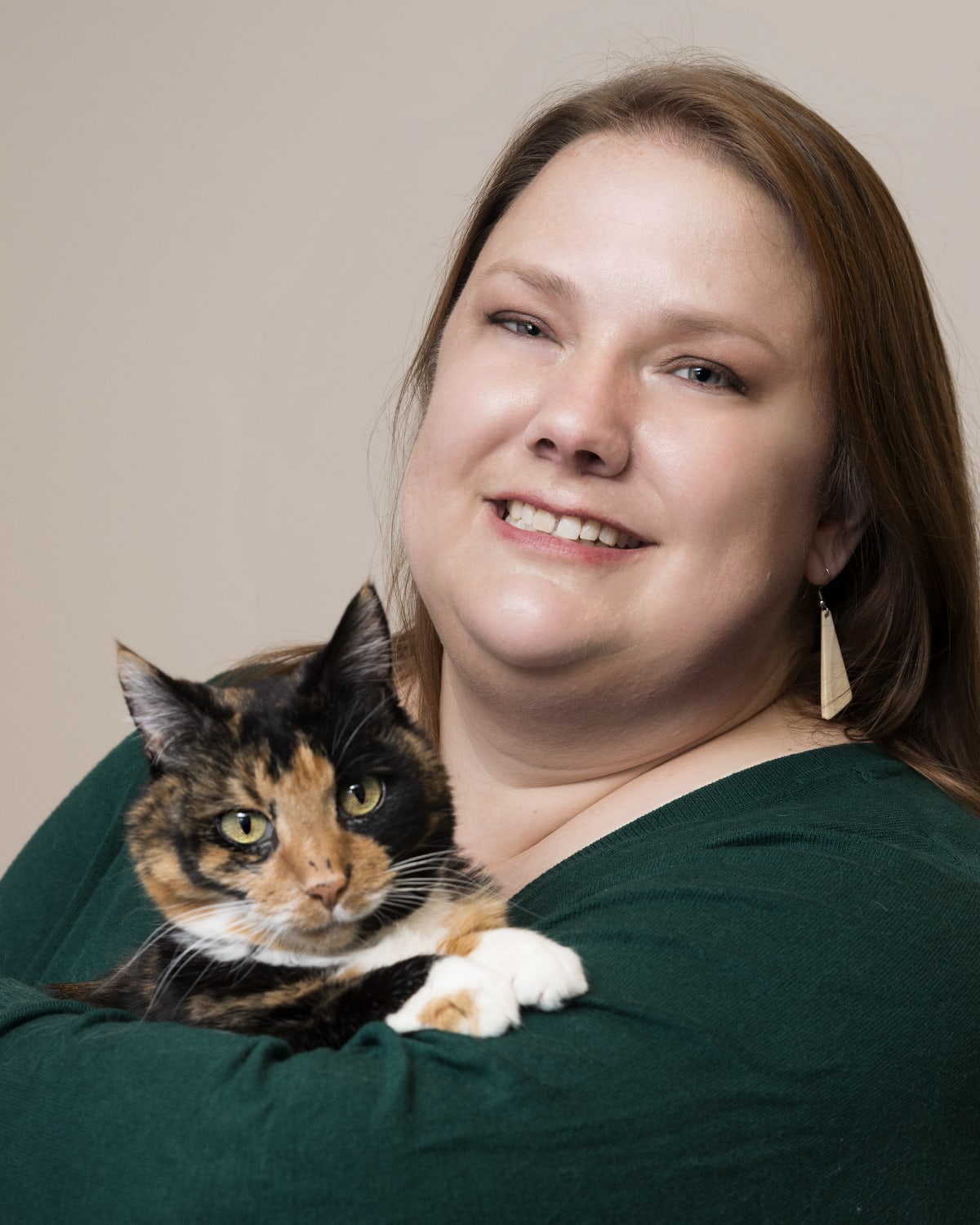 A headshot of Karen Green wearing a green shirt and holding a calico cat.