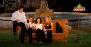 A screenshot from the opening credits of the television series Friends has been edited to include a black cat on the edge of the sofa next to the actors.