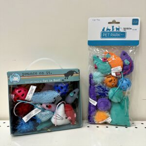 Toy mice, small plastic balls containing bells, and fuzzy balls packaged in a box (on the left) and in a bag (on the right) from two different pet brands.