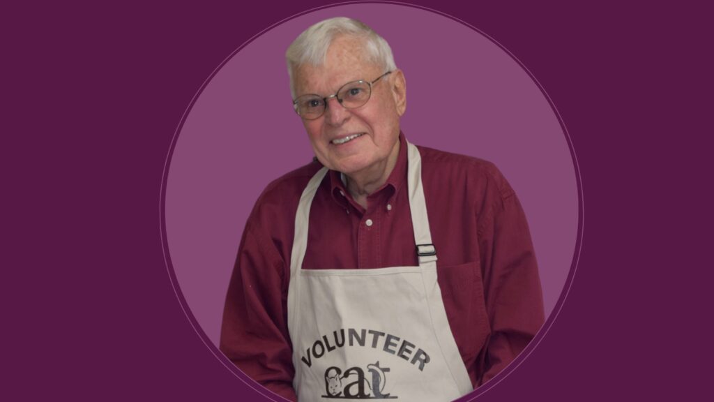 Over a light purple circle and eggplant-colored background is a headshot of Jeff wearing glasses, a burgundy shirt, and CAT Volunteer apron