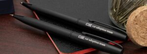 CAT's logo is visible on two black pens that are sitting on desk.