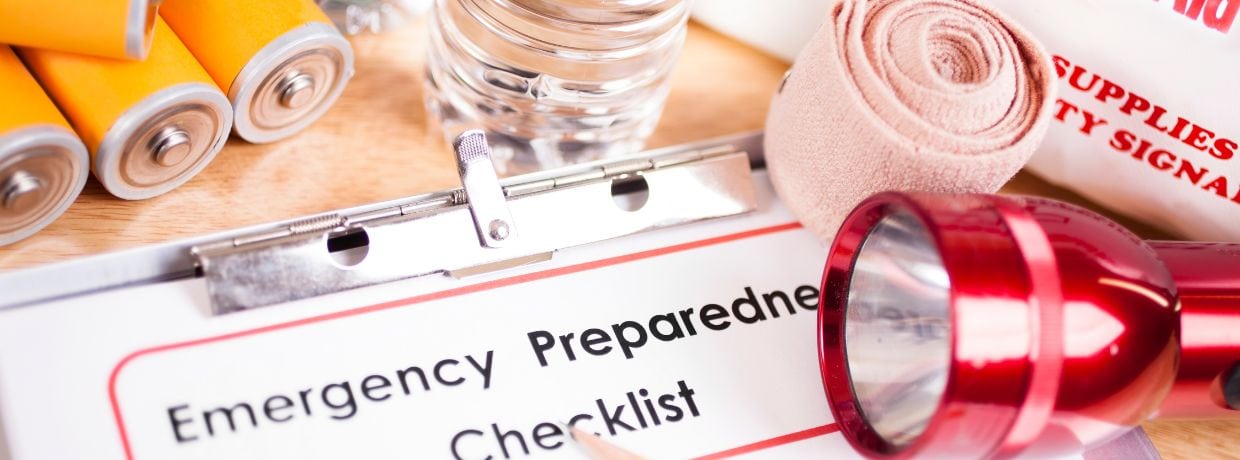 Collage features batteries, a red flashlight, and other emergency supplies including a clipboard with paper that reads: Emergency Prepardness Checklist.