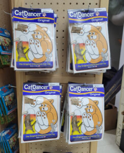 Wooden peg display board of 4 stacks of Cat Dancer toys with an illustration of a cat jumping and playing featured on packaging.