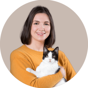 A headshot of Brittany Perkins holding a black-and-white cat. She is wearing a yellow sweater.