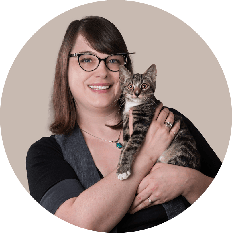 Headshot of Bobbie Winchell. She wears glasses and is holding a tabby kitten near her face.