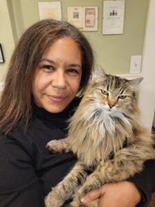 a person with dark hair holds a fluffy brown tabby cat to their chest.