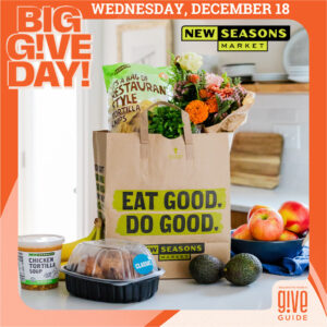 Big Give Day! A New Seasons Market paper bag filled with and surrounded by grocery products.