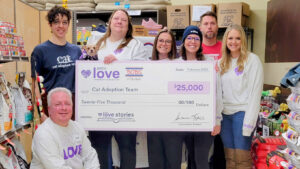 A group of people gathers around a giant check for $25,000 from Petco. They smile and look at the camera.